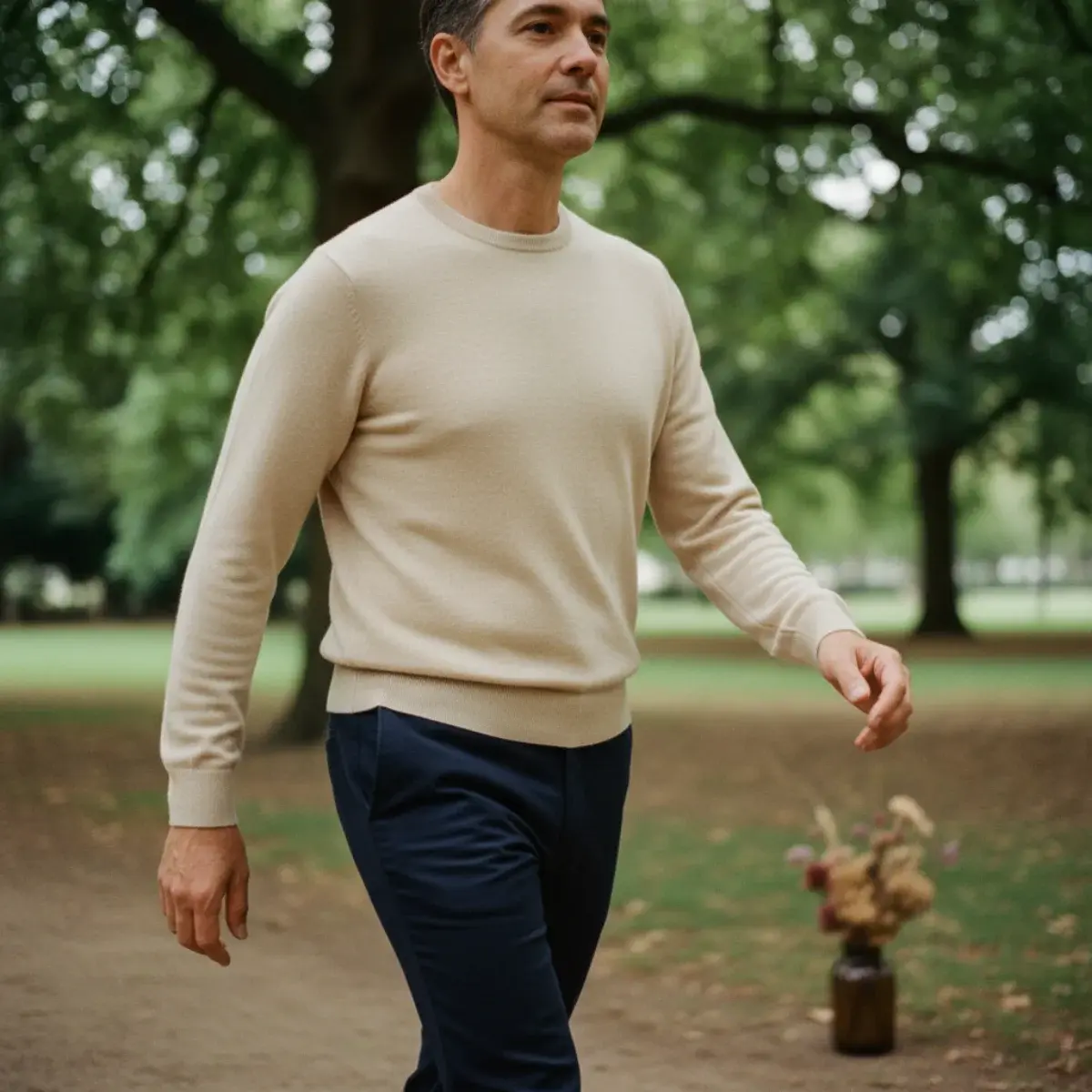 A natural-coloured linen camp-collar shirt half-buttoned over a white t-shirt, paired with sand-coloured linen trousers and tan leather sandals