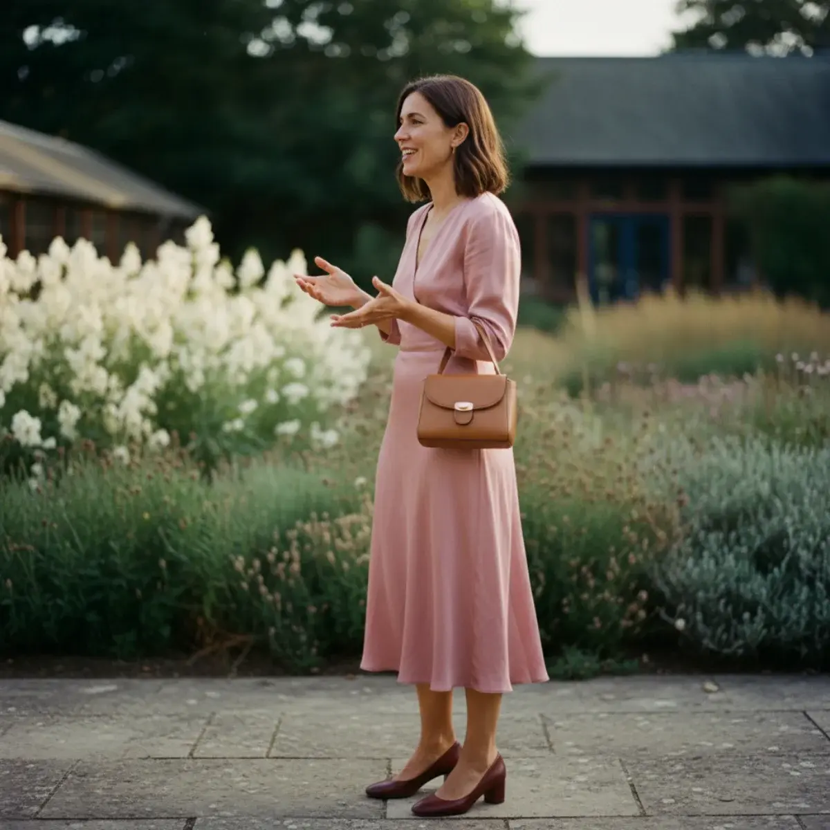 Woman in a midi wedding-guest dress with block heels and a clutch at an outdoor venue