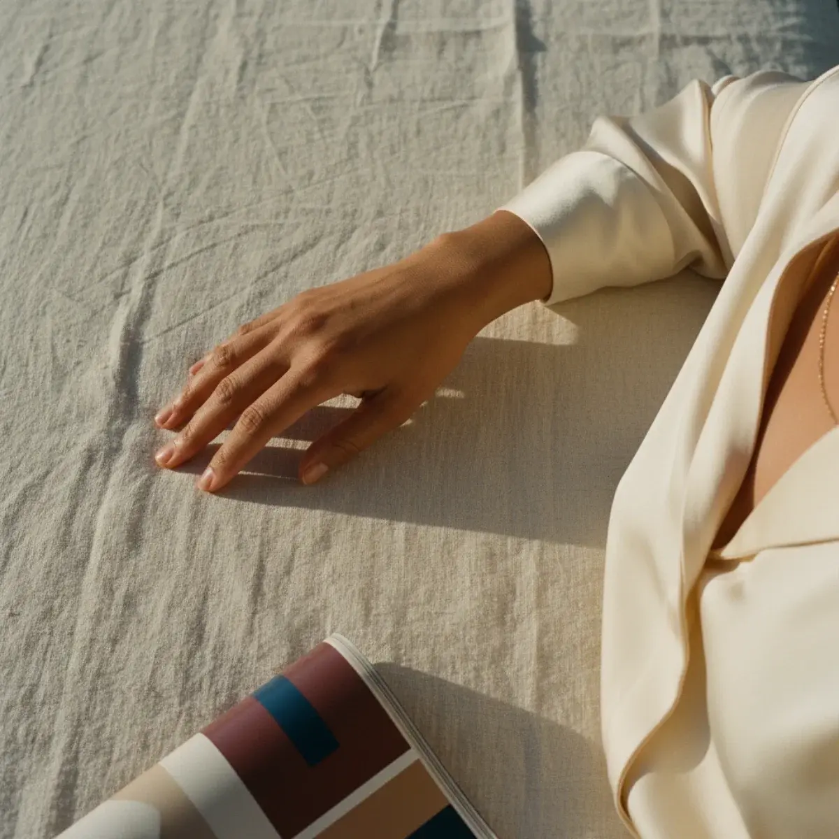 Woman in an ivory silk slip dress with a tailored coat over the shoulders, evening light