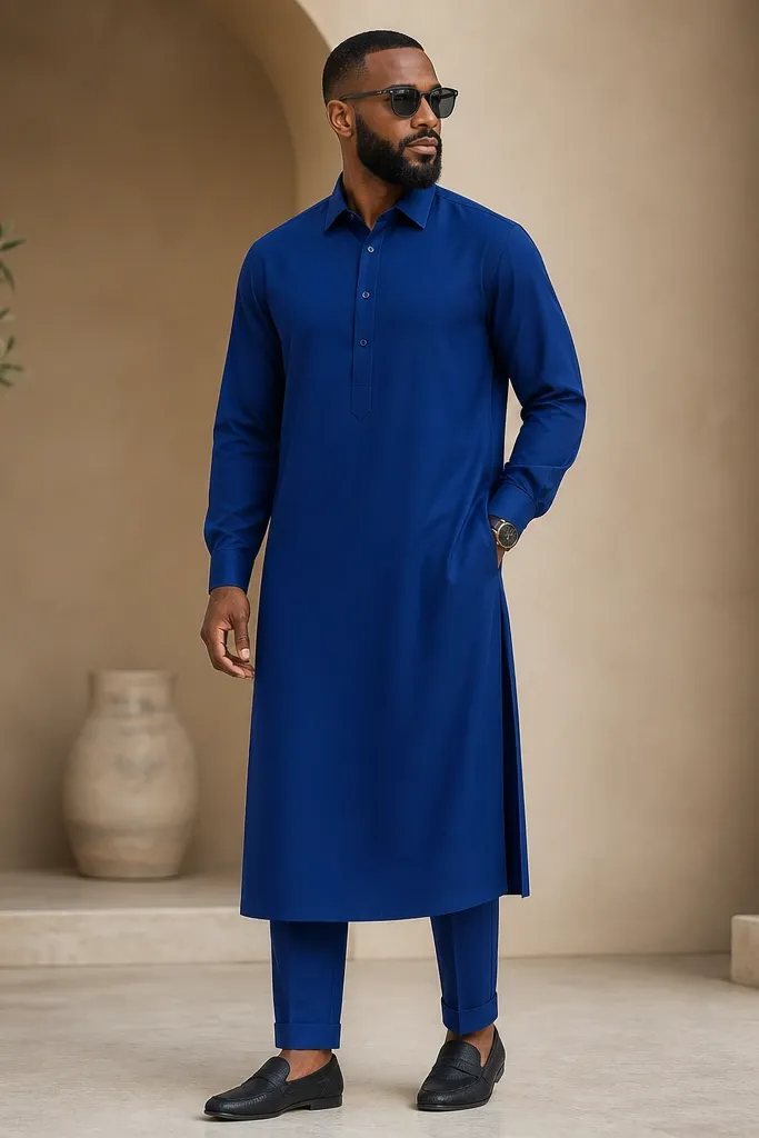A royal blue tailored kaftan with a neat collar and a front button placket. The sleeves are loose at the shoulder but taper at the cuff. The hem lands around the ankle. The trousers are slim with cuffed hems and match the kaftan color family.