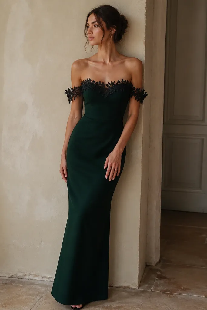 A midnight green off-shoulder dress with a fitted bodice. The edges of the neckline and the sleeves have botanical lace trim in black thread. The skirt is straight and falls to the ankles.