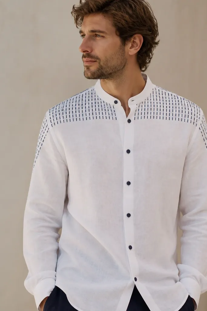 A white linen shirt with a navy dash print across the upper yoke area and down the shoulder seams. The rest of the shirt is plain white. It has a slim collar and navy buttons.