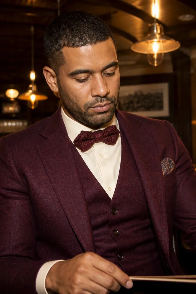 Burgundy three-piece suit with cream shirt and burgundy knit bow tie